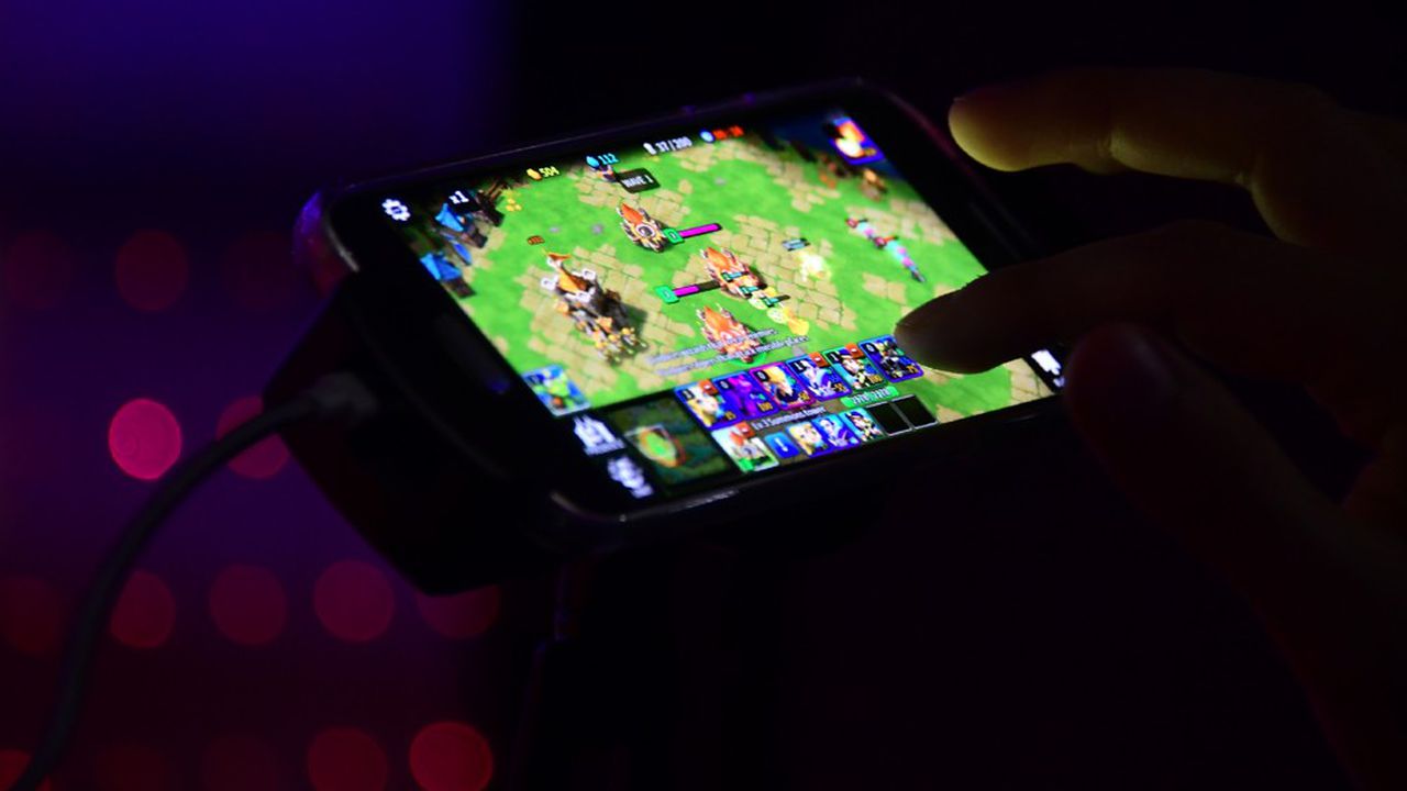 personne jouant à un jeu vidéo sur smartphone avec interface de jeu visible