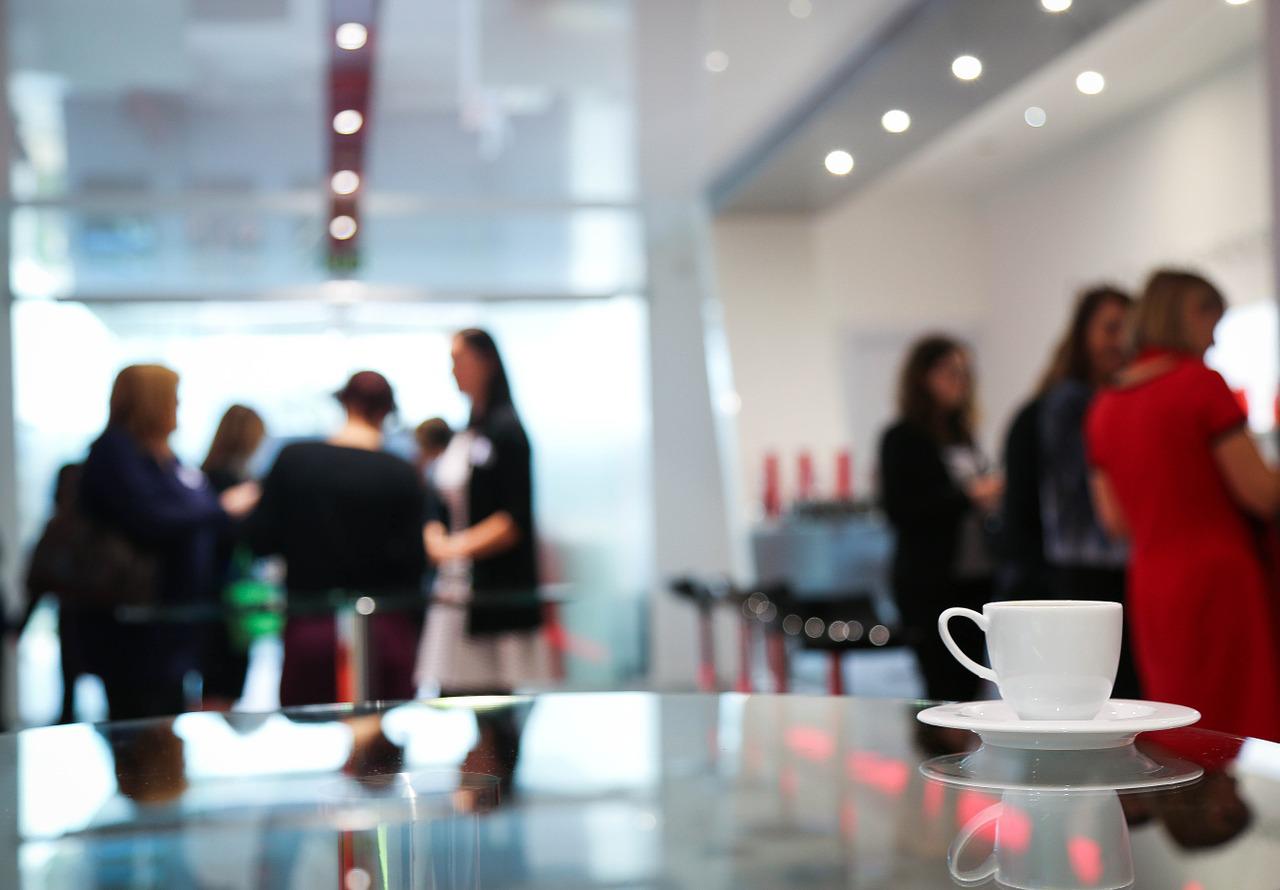 tasse de café blanche sur table lors d'une conférence marketing