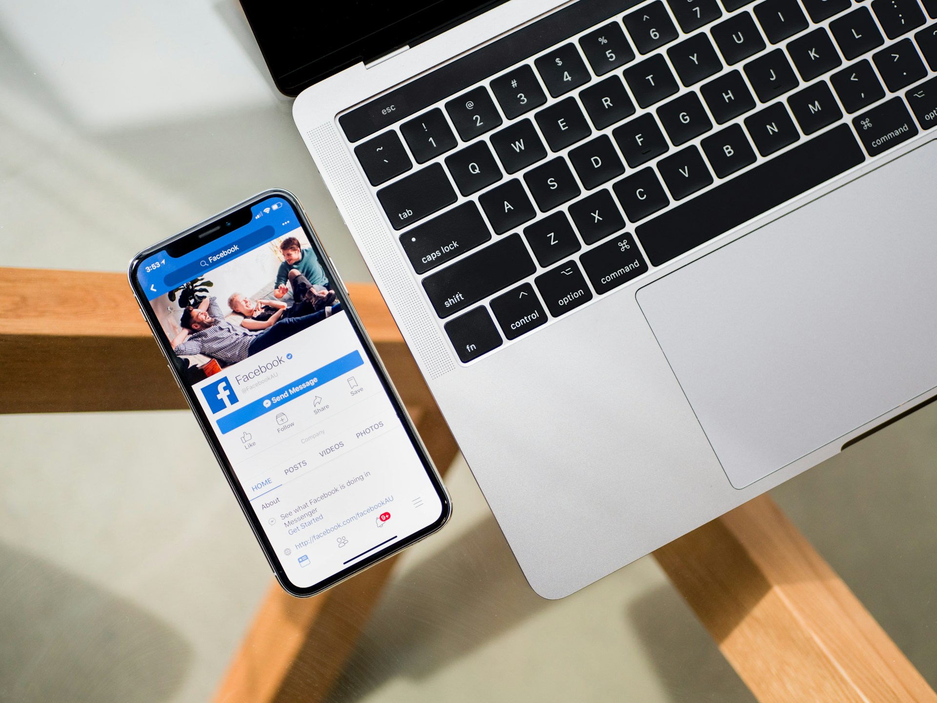 téléphone affichant la page facebook avec ordinateur portable sur un bureau en bois