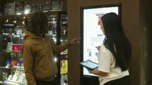 deux personnes interagissent avec un écran tactile interactif en magasin