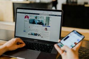 personne consultant un profil de réseau social sur macbook pro et smartphone pour stratégie marketing digital