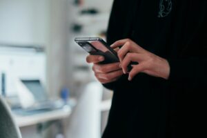 personne tenant un smartphone noir dans un environnement professionnel moderne